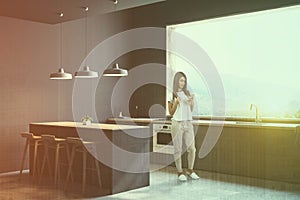 Woman in gray kitchen corner with bar and stools