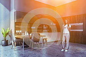 Woman in gray kitchen with ovens and table