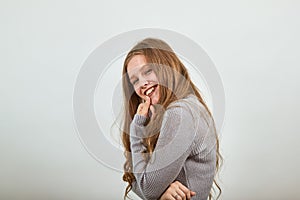 Woman in gray sweater is hunched over and smiling shyly holding chin in her hand