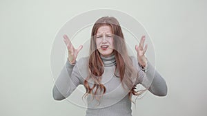 Woman in gray sweater reacts irritably, an angry expression on face waving hands