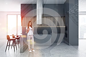 Woman in gray and wooden kitchen with bar