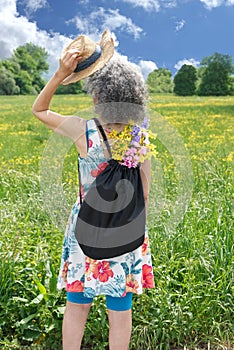 Woman with graying hair standing in a field under sunlight