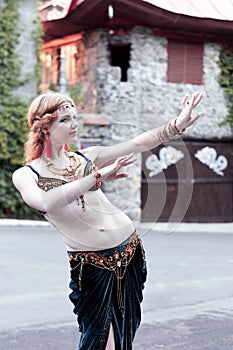 Woman in green belly dance costume with outstretched hands looking away