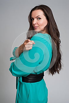 Woman in green dress pointing at you