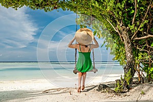 Woman in green dress swinging at beach