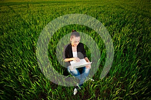 Woman in a green field with a laptop. summer