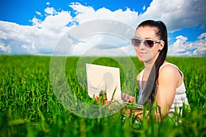 Woman in a green field with a laptop. summer