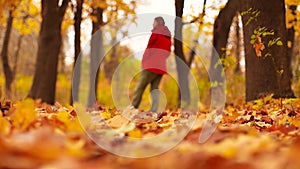 Woman green jeans and grey boot walking on dry fallen leaves in autumn forest. Close-up