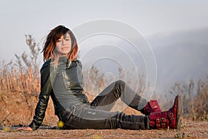 Woman in green leather jacket seated on ground