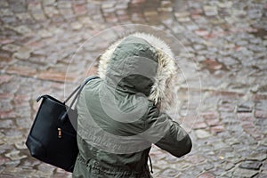 woman with green rain coat walking in the street