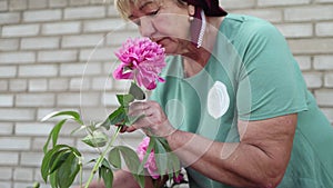 Woman in green shirt holding pink flower at an event