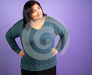 A woman in a green shirt is standing with her arms crossed and looking away