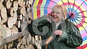 Woman in green slicker with umbrella and cell phone