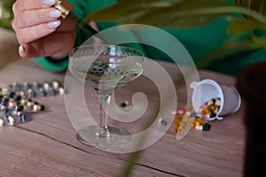 a woman in a green sweater adds drops of chlorophyll to a glass of water standing next to palm trees