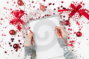 Woman in grey sweater writting checklist of plans and dreams for next year. Wish list for Christmas. To Do List for New 2020 year