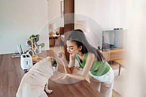 Woman in green tank attentively engaging with a pug at home