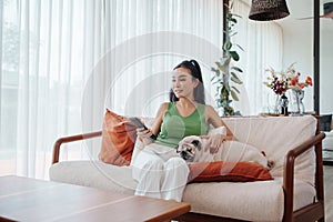 Woman in Green Top Petting Dog and Holding Remote Control