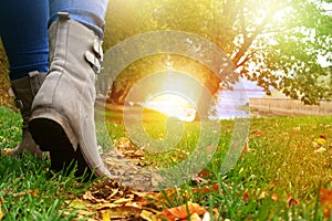 Woman in grey shoes and jeans walking on the autumn forest path