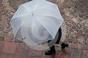 woman with grey umbrella on cobbles place in the ci