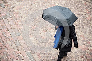 Woman with grey umbrella on cobbles place in the ci