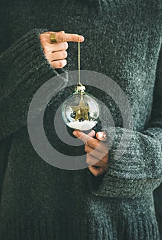 Woman in grey warm woolen sweater holding decorative glass ball