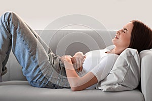 woman gripping belly in pain having painful menstrual cramps indoors
