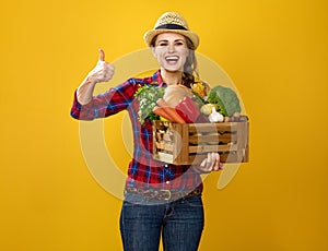 Woman grower with box of fresh vegetables showing thumbs up