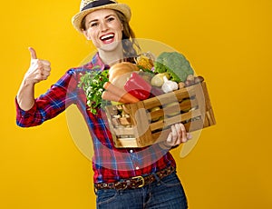 Woman grower with box of fresh vegetables showing thumbs up