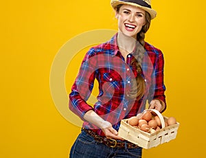 Woman grower isolated on yellow background basket with eggs
