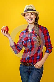 Woman grower isolated on yellow background showing an apple