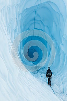 Woman on a guided trip to the Matanuska Glacier in Alaska exploring a large ice cave