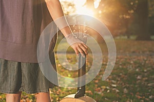 Woman with guitar at sunset in park