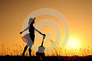 Woman and guitar with sunset silhouette