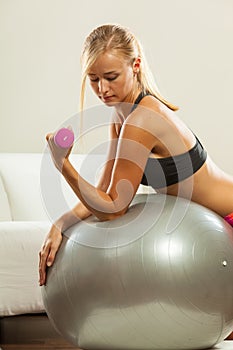 Woman with gym ball and dumbbell doing exercise