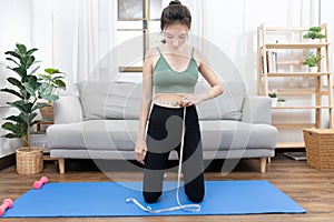 Woman in a gym clothes uses a centimeter strap to measure her circumference thin waist