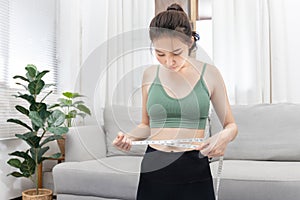 Woman in a gym clothes uses a centimeter strap to measure her circumference thin waist