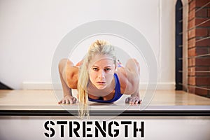 Woman In Gym Doing Press-Ups On Step Labeled Strength