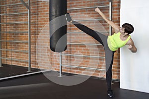 Woman in the gym kicks a foot on a punching bag