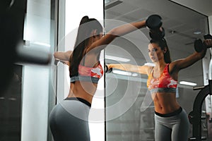 Woman in gym lifts dumbbells