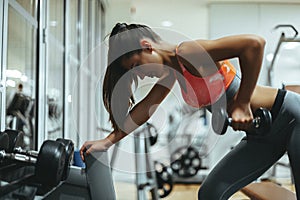 Woman in gym lifts dumbbells