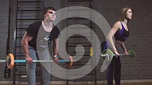 Woman in gym with personal fitness trainer exercising power gymnastics with a barbell