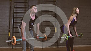 Woman in gym with personal fitness trainer exercising power gymnastics with a barbell