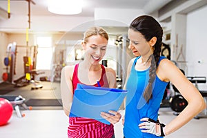 Woman in gym, personal trainer, consultiing plan on clipboard