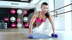 Woman at gym push up push-up workout exercise with dumbbells. Dolly shot