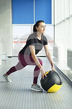 woman in gym relaxing with medicine ball