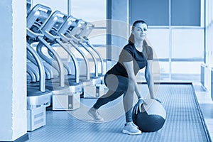 woman in gym relaxing with medicine ball