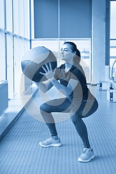 woman in gym relaxing with medicine ball