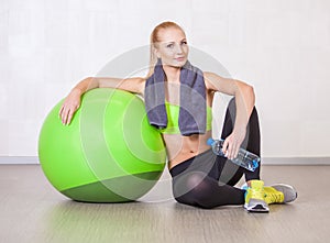 Woman in a gym resting after training with fitness ball