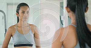 Woman at the gym struggling with her weight in front of the mirror