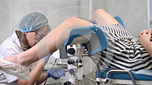 Woman gynecologist examining female patient using colposcope